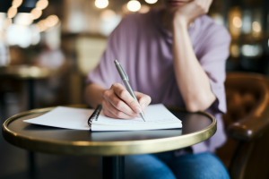 personne-carnet-stylo-cafe-flou